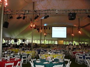 This gala of ~900 used a tent with sides that offered windows. The sides helped contain the sound while allowing guests to feel outside. Note the rigging.